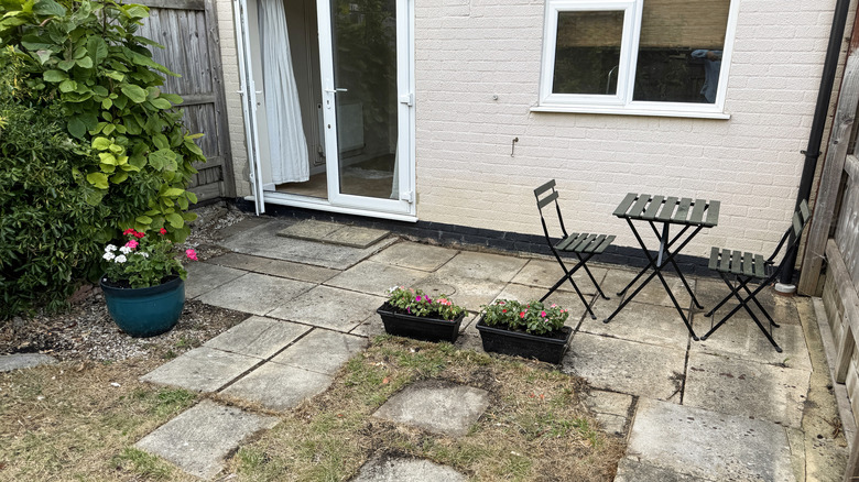 A patio set and planters sit on a dingy old concrete patio