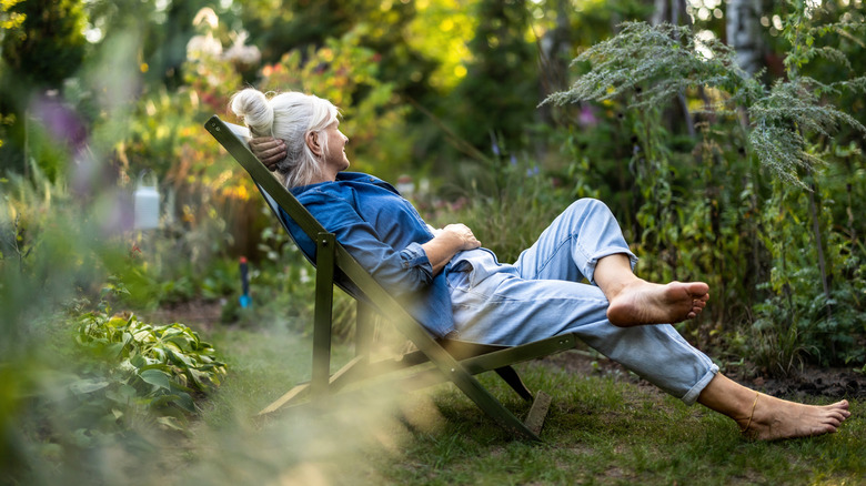 A person relaxing in a chair in a lush garden
