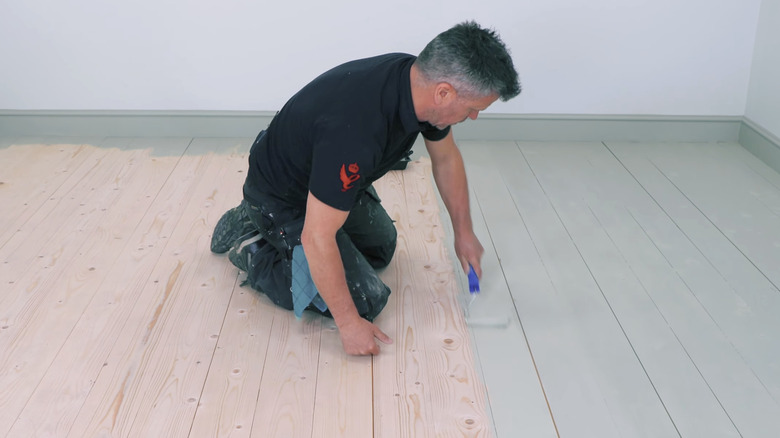 Person painting a hardwood floor
