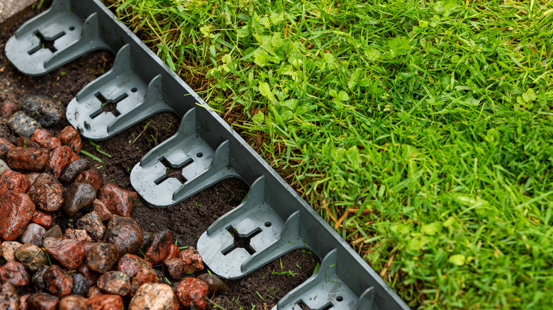 Plastic edging between lawn grass and decorative pebbles
