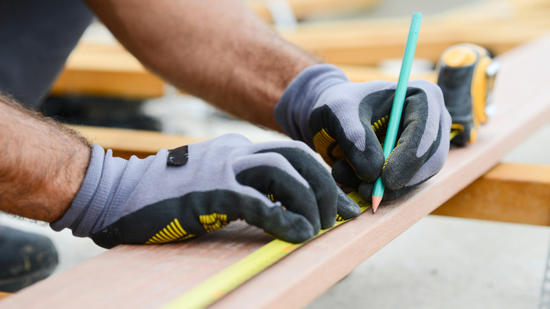 Person measuring a flat wood board before making a cut