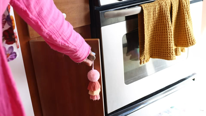 Person opening the door on a narrow cabinet next to the stove