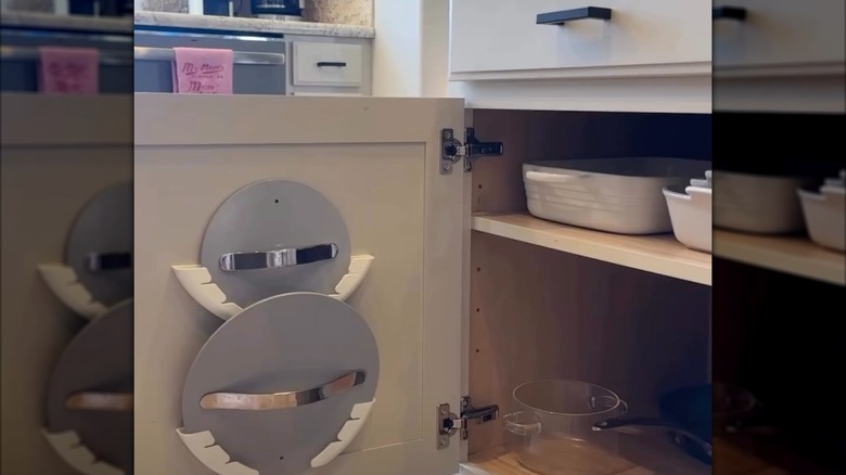 Pot lids hanging on a cabinet door with the help of adhesive holders