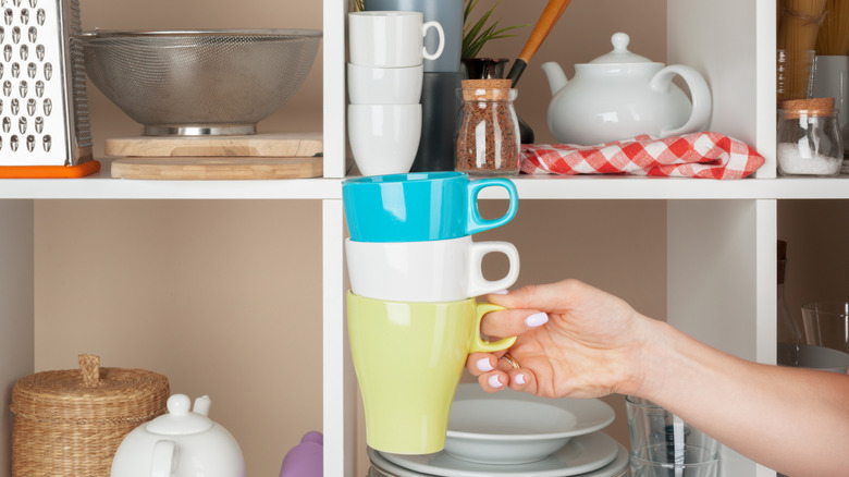 A hand holding stacked coffee mugs