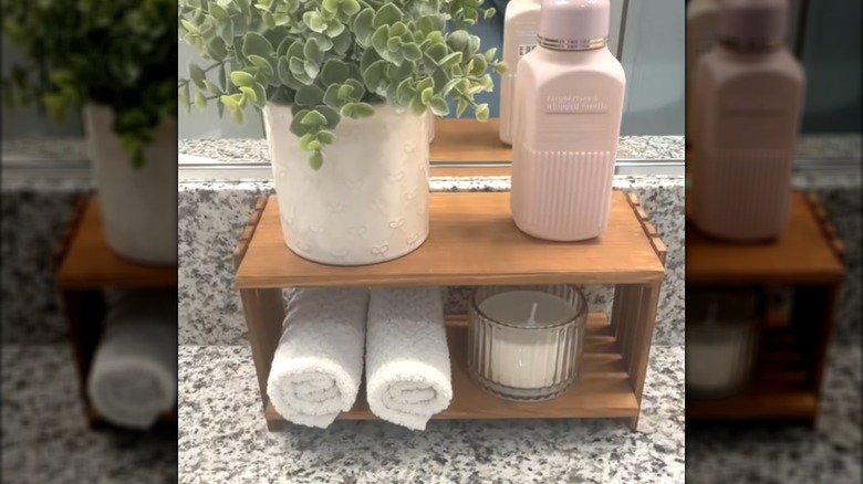 Wooden Dollar Tree storage shelf with white plant pot, soap, hand towels, and tealight candle in bathroom