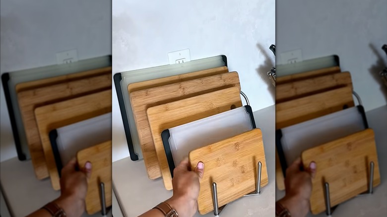 a person stores wooden cutting boards on an IKEA pot lid holder