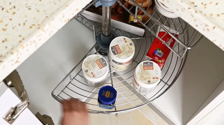 Person spinning a meal lazy susan rack inside a lower corner cabinet