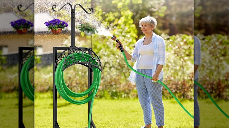 Woman spraying a hose next to a hose holder