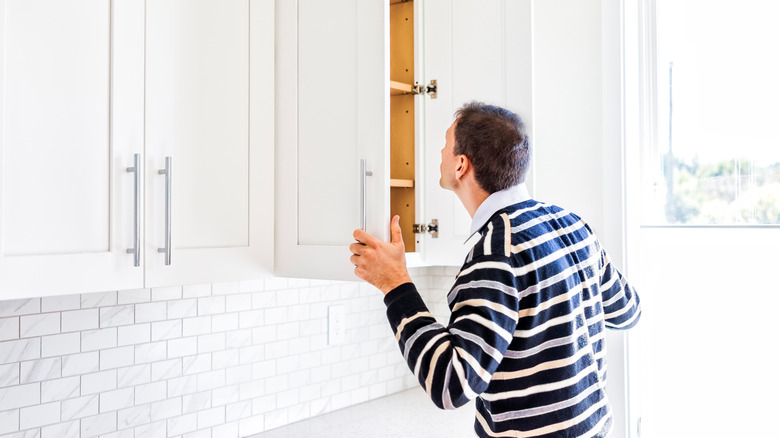 A person looking into an open kitchen cabinet