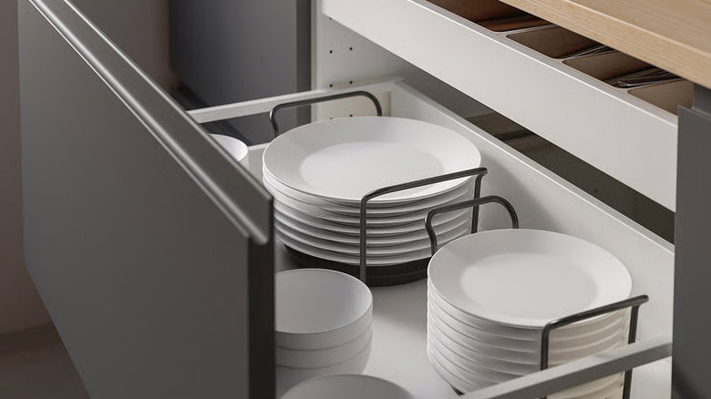 Stacks of white plates sit inside anthracite UPPDATERA Plate holders in a deep kitchen drawer
