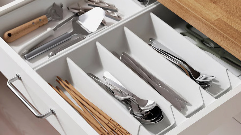 Chopsticks, silverware, and assorted utensils are organized in a large kitchen drawer
