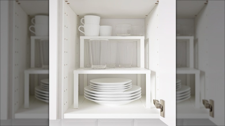 White coffee cups and glasses sit on a VARIERA Shelf insert in a deep white kitchen cabinet