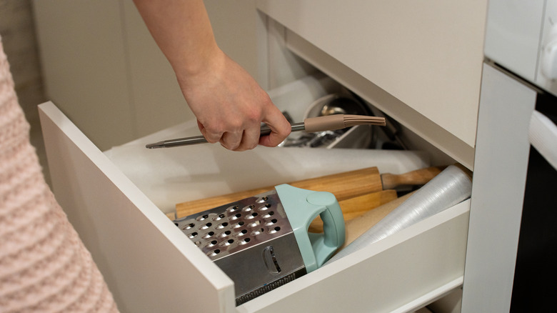 Person reaching into a kitchen drawer