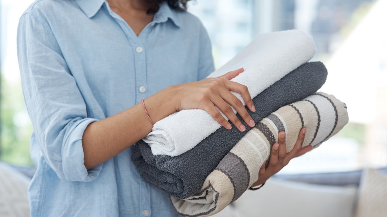 A woman holding a stack of clean folded towels