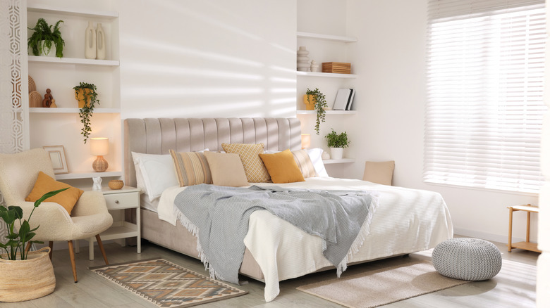 A bedroom with white walls and sunlight streaming in through the window