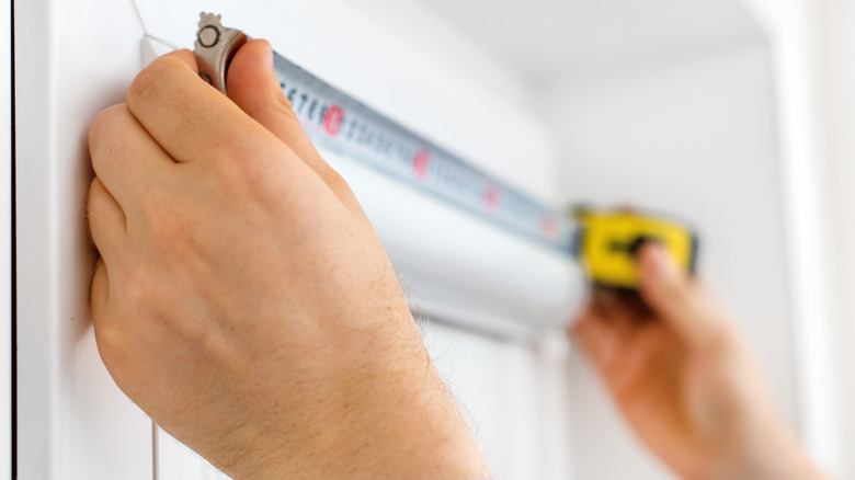 A person measuring a window
