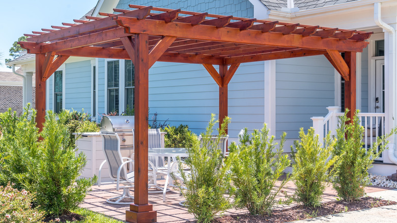 Wooden pergola over patio furniture in garden