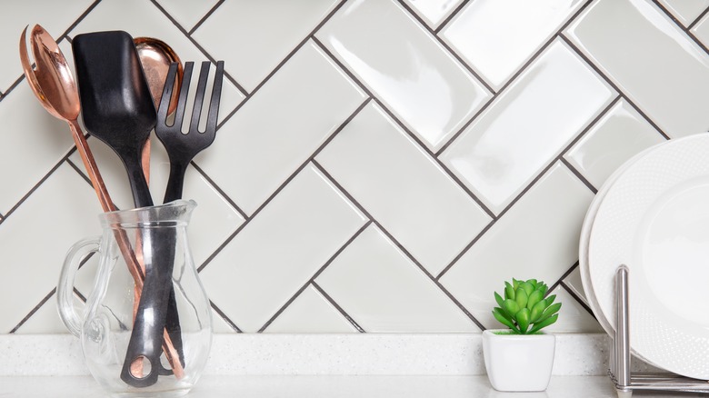 a shiny tile backsplash and kitchen utensils