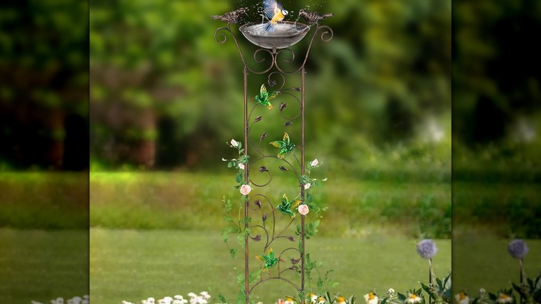 A vertical bird feeder and trellis in a green backyard