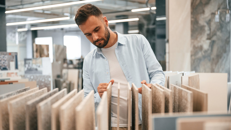 A man in a homeware store looking at white tile samples