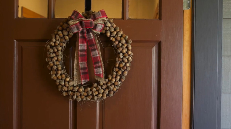 a homemade acorn wreath hanging on a front door