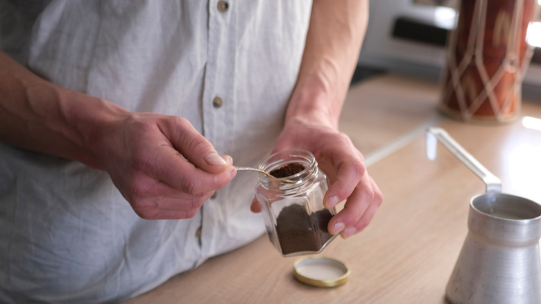 Man spooning coffee grounds into a jar