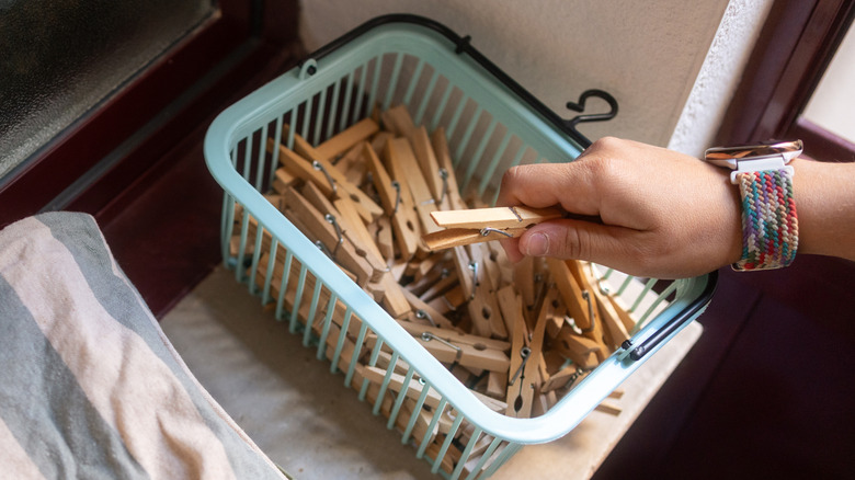 A person taking a clothespin from a basket full of them
