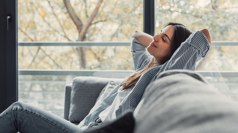 Woman relaxing on living room couch and breathing in fresh air
