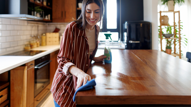 Woman cleaning her wood kitchen countertops with a cloth