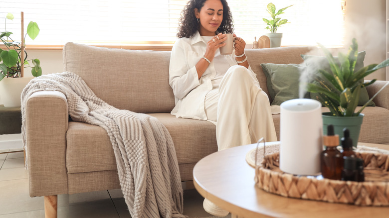 Woman relaxing on a couch with an essential oil diffuser running