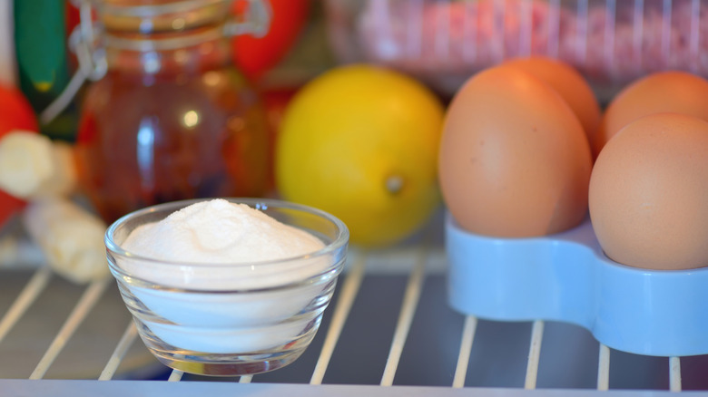 Bowl of baking soda in a refrigerator next to eggs