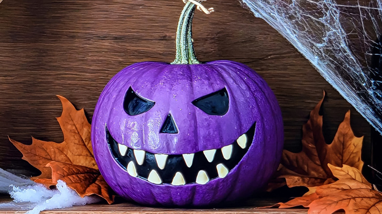 pumpkin painted as a purple Jack-o'-lantern