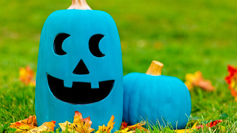 teal and black painted jack-o-lantern sitting on the grass