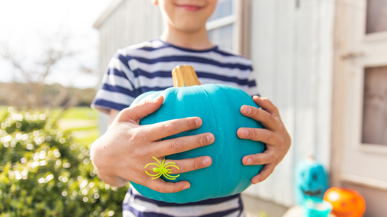 a teal plastic pumpkin next to a skeleton dog on steps