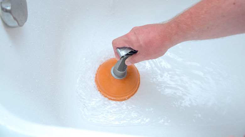 Unclogging a tub drain with an orange plunger