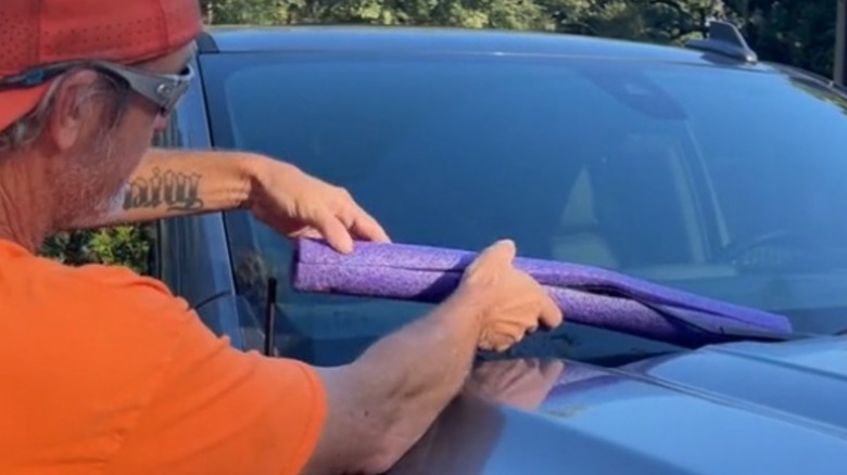 Man covering windshield wiper with part of a pool noodle