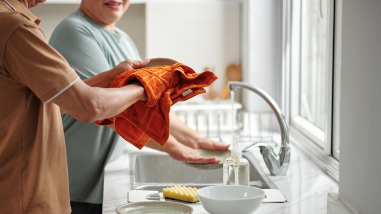Couple washing and drying dishes at the kitchen sink