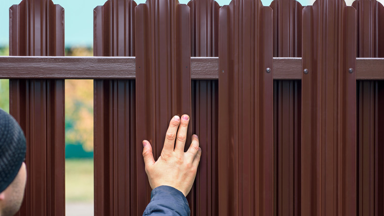 person with hand against a fence post during installation
