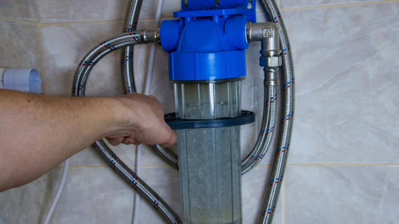 Hand holding a water softener system in place during installation