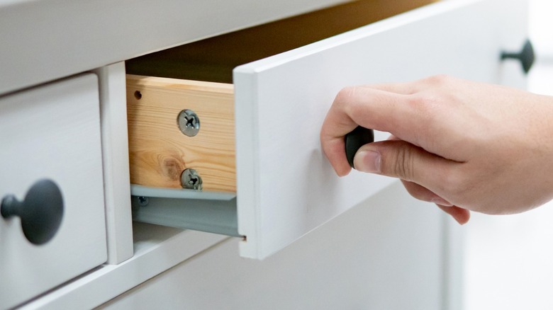 Hand opening drawer on white cabinet with matte black hardware