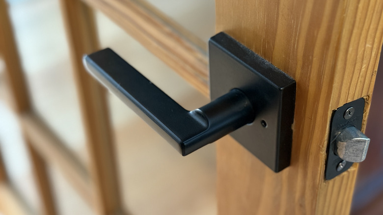 Matte black door handle on a wood door