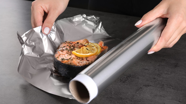 Rolls of aluminum foil being manufactured on large industrial rollers.