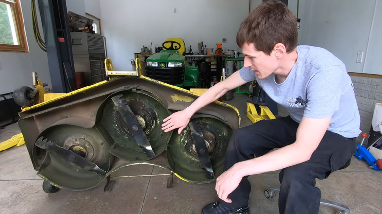 young man shows the results of his lawn mower deck undercoating product test