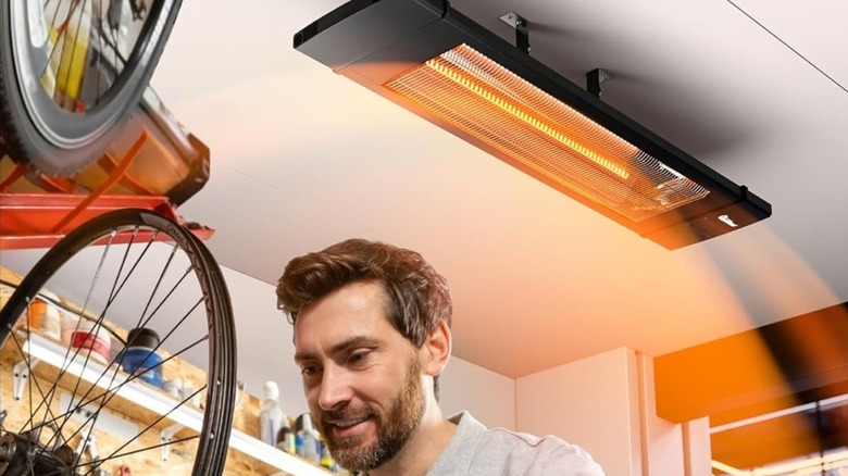 Person working in a garage with the heater mounted on the ceiling