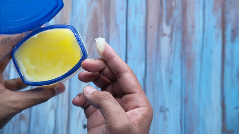 Person dipping finger in jar of petroleum jelly