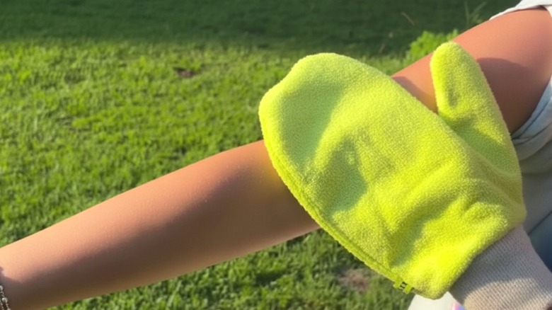 A woman gliding the Tick Mitt over her skin