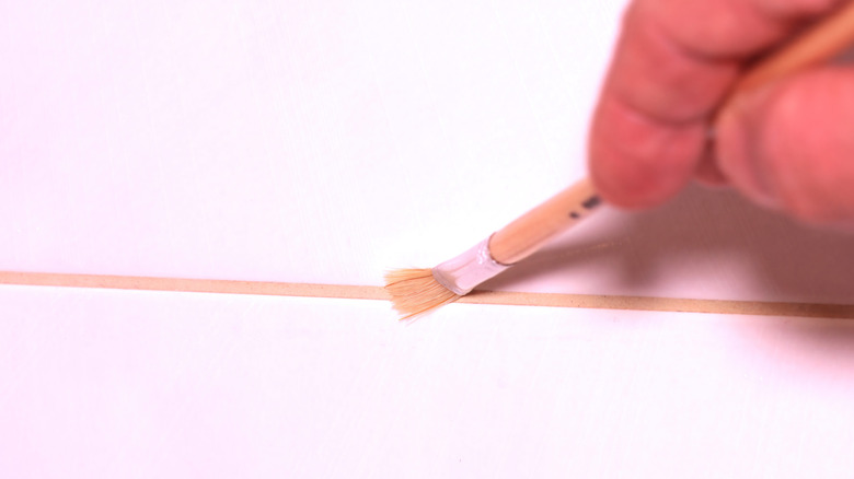 hand using a brush to apply sealer to tile grout