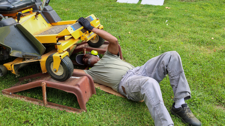 A man servicing his riding lawn mower