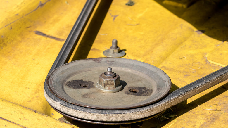 A damaged belt on a yellow lawnmower