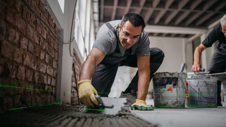 Worker laying concrete tiles